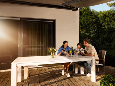 Familie sitzt im Außenbereich an einem Tisch
